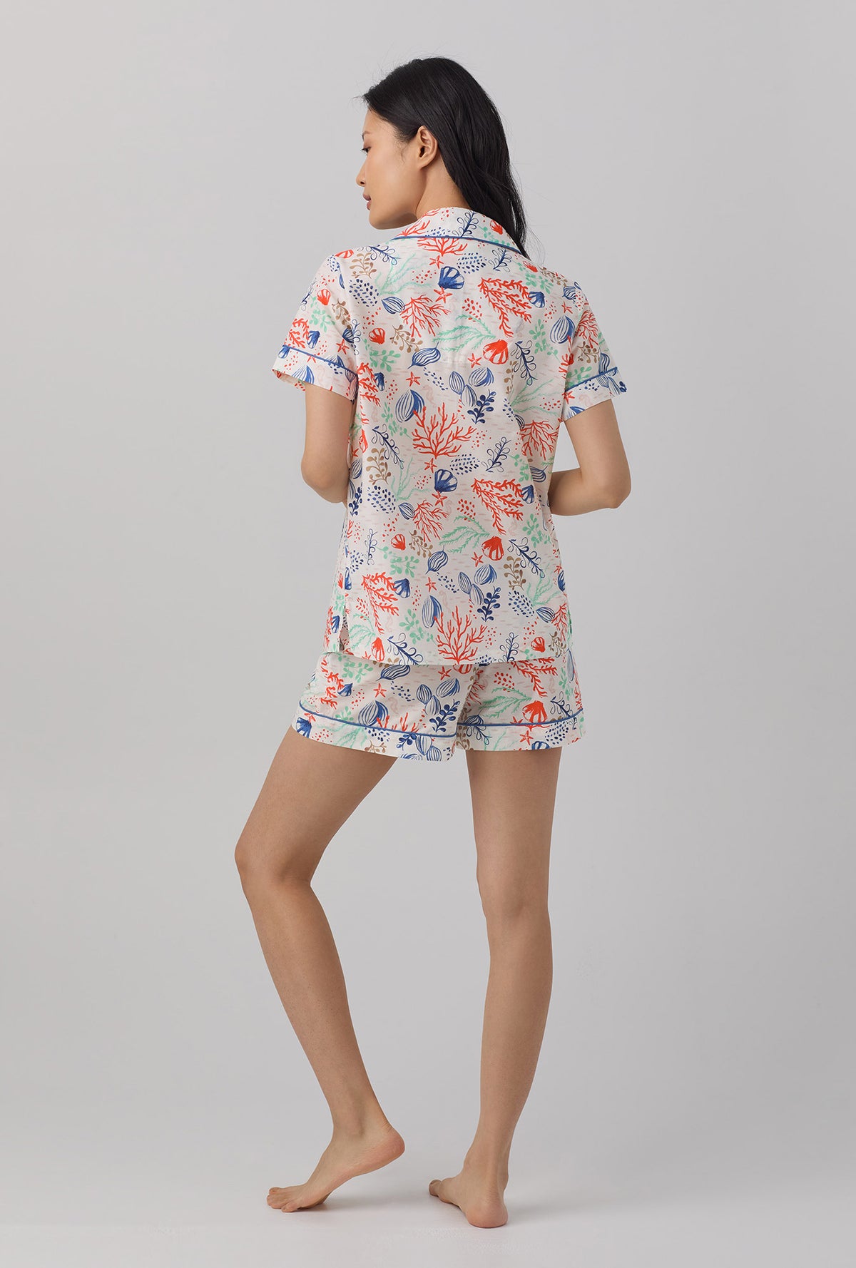 A lady wearing short sleeve classic pj set with coral reef print.