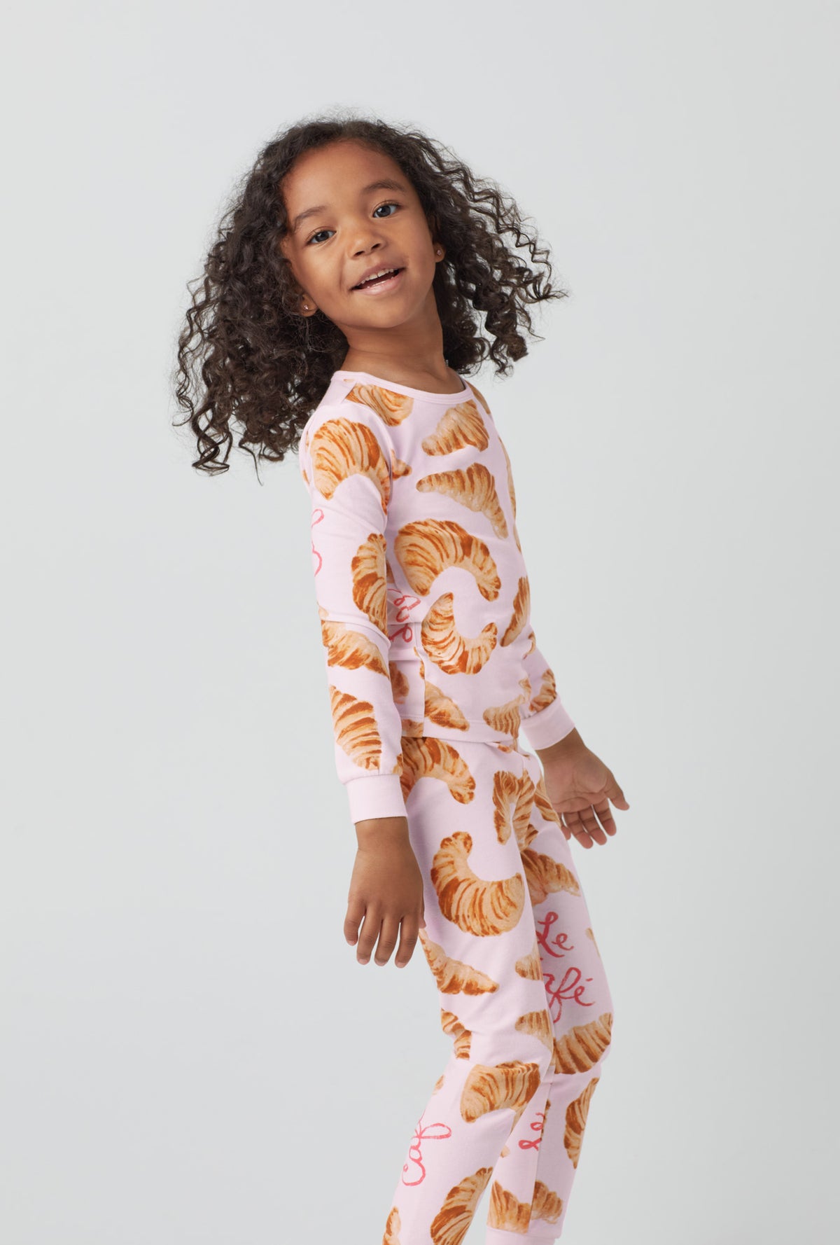 A girl wearing orange  Long Sleeve Stretch Jersey Kids PJ Set  with Le Cafe  print.