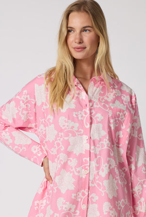 A Lady Wearing Dynasty Pink High Low Woven Cotton Poplin Boyfriend Shirt in a close up view pose