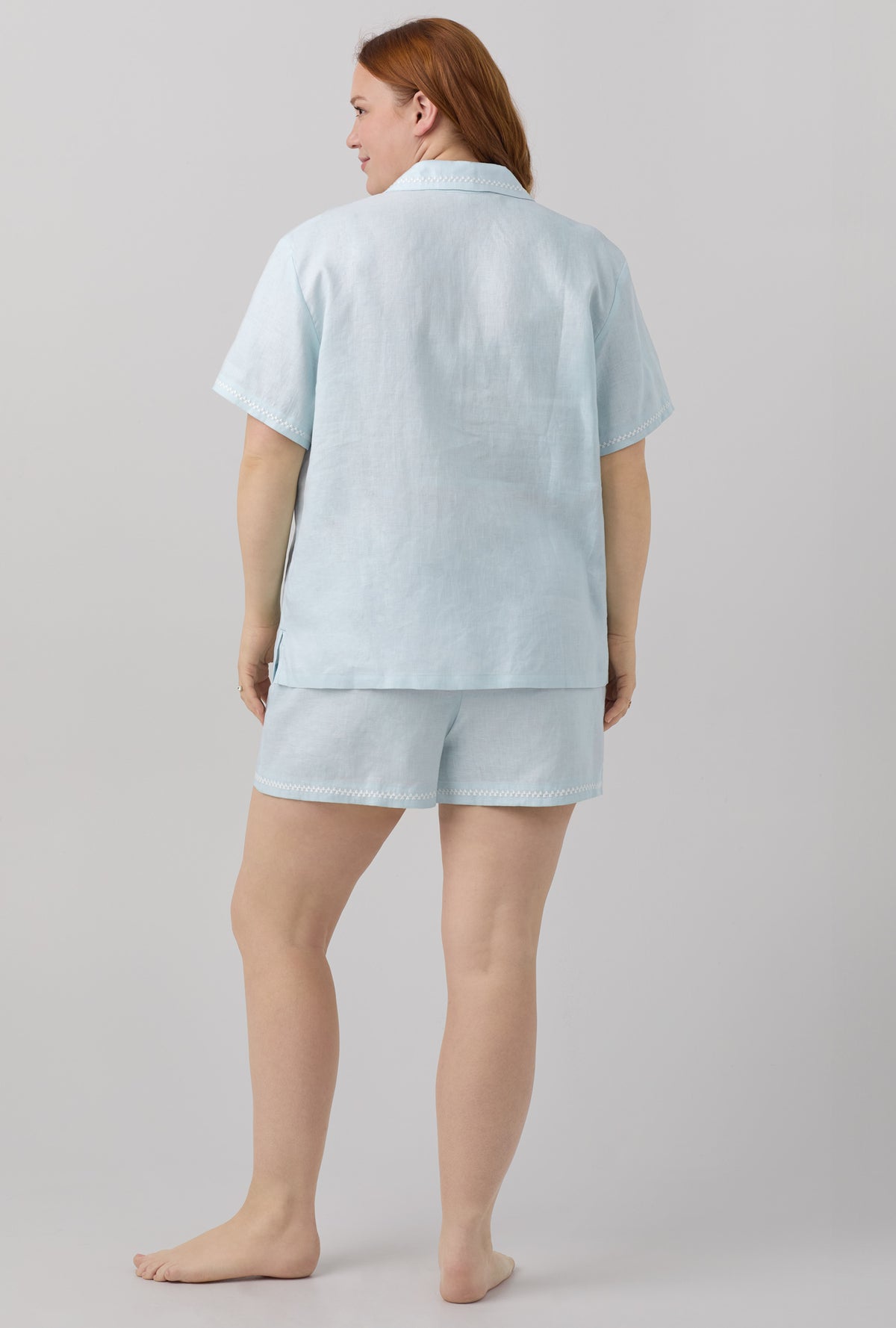 A lady wearing blue short sleeve classic shorty woven linen plus size pj set with delicate blue print.