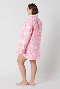 A Lady Wearing Plus Size Dynasty Pink High Low Woven Cotton Poplin Boyfriend Shirt in a side standing pose