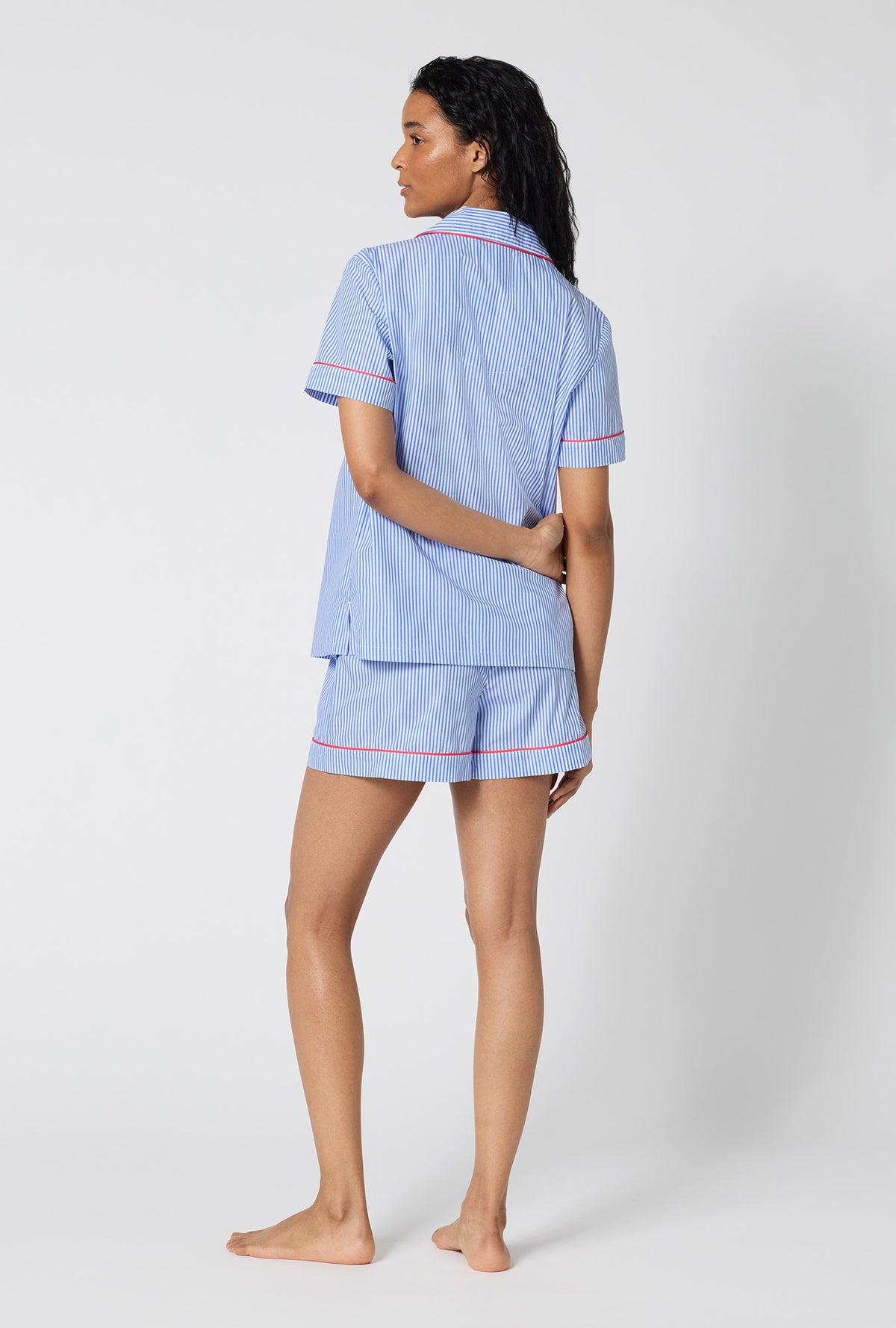 A Lady Wearing French Stripe Short Sleeve Classic Woven Supersoft Cotton Poplin Shorty Pj Set in a back view pose while looking to the side