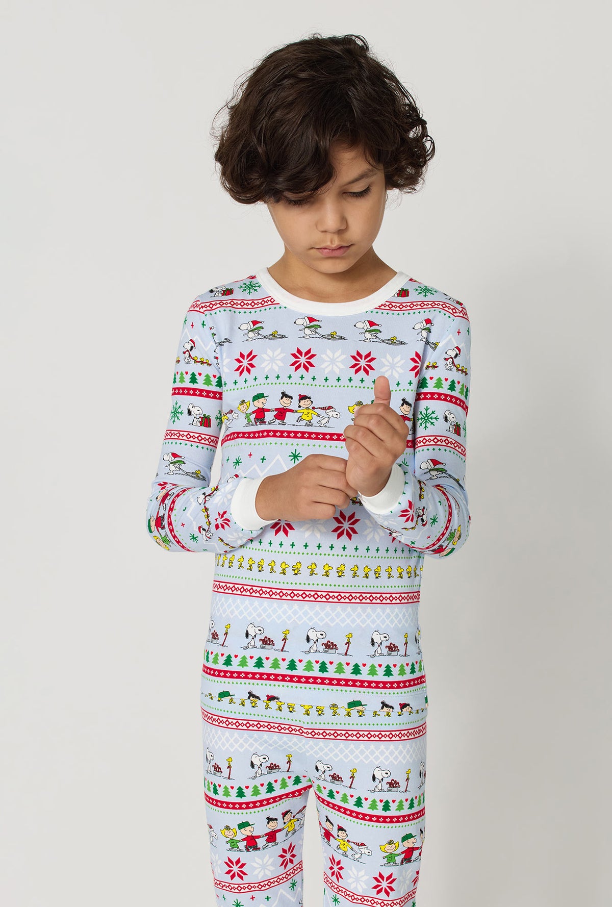 A boy wearing Peanuts® Winter Parade Long Sleeve Stretch Jersey Kids Pj Set closer look