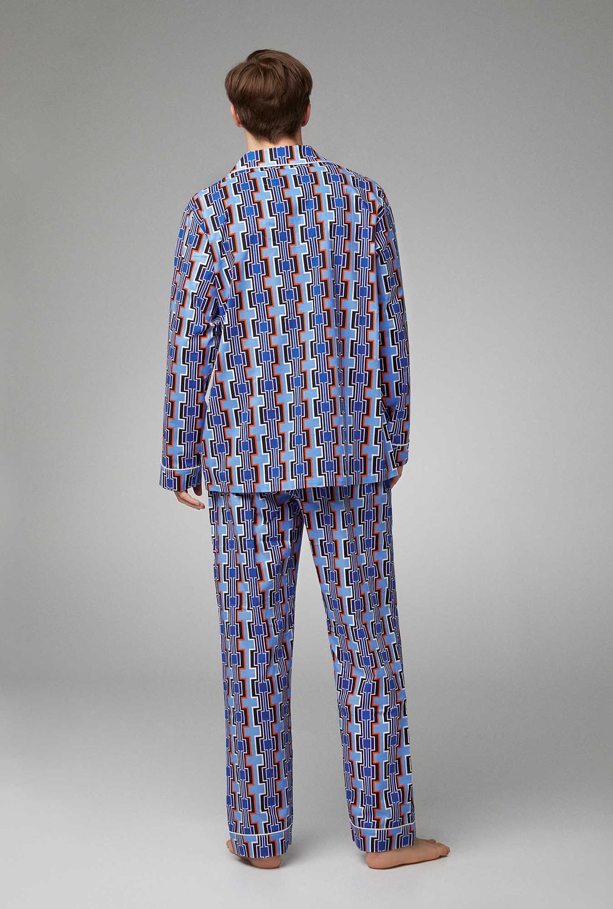 A man wearing blue long sleeve classic woven poplin pj set with santa inaz print.