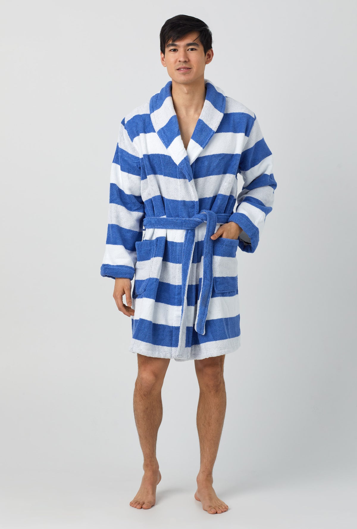 A man wearing white and blue unisex woven cotton loop turkish terrry jacquard short robe with seaside stripe print.