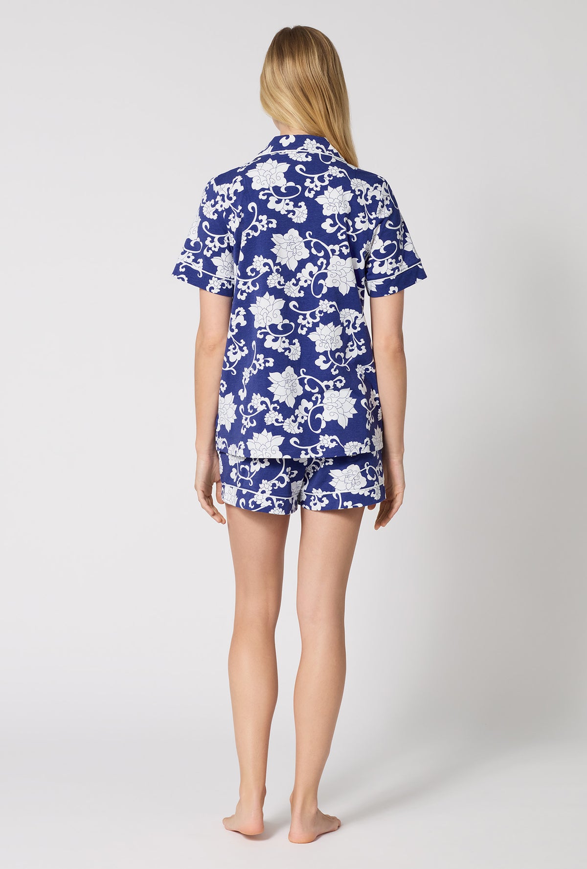 A Lady Wearing Dynasty Blue Short Sleeve Classic Shorty Stretch Jersey Pj Set in a back view pose