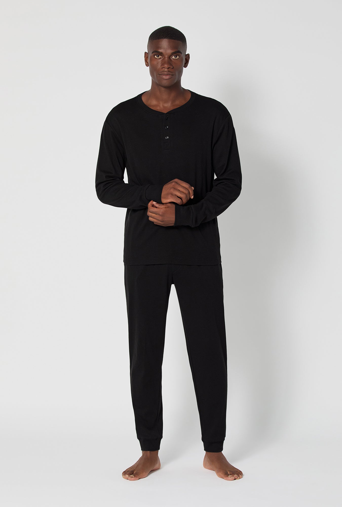A man wearing Black Beauty Men's Long Sleeve Henley And Jogger Cotton Rib Pj Set
