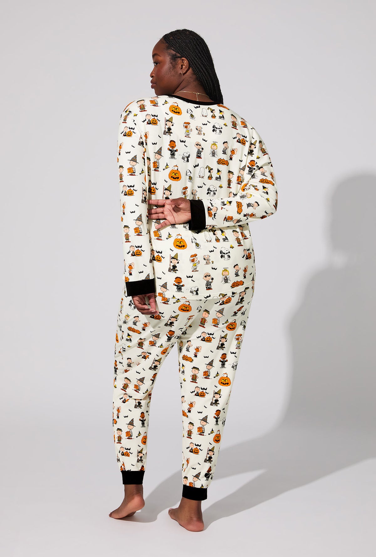 A lady wearing Peanuts® Snoopy&#39;s Halloween Long Sleeve Pullover Crew and Jogger Stretch Jersey PJ Set