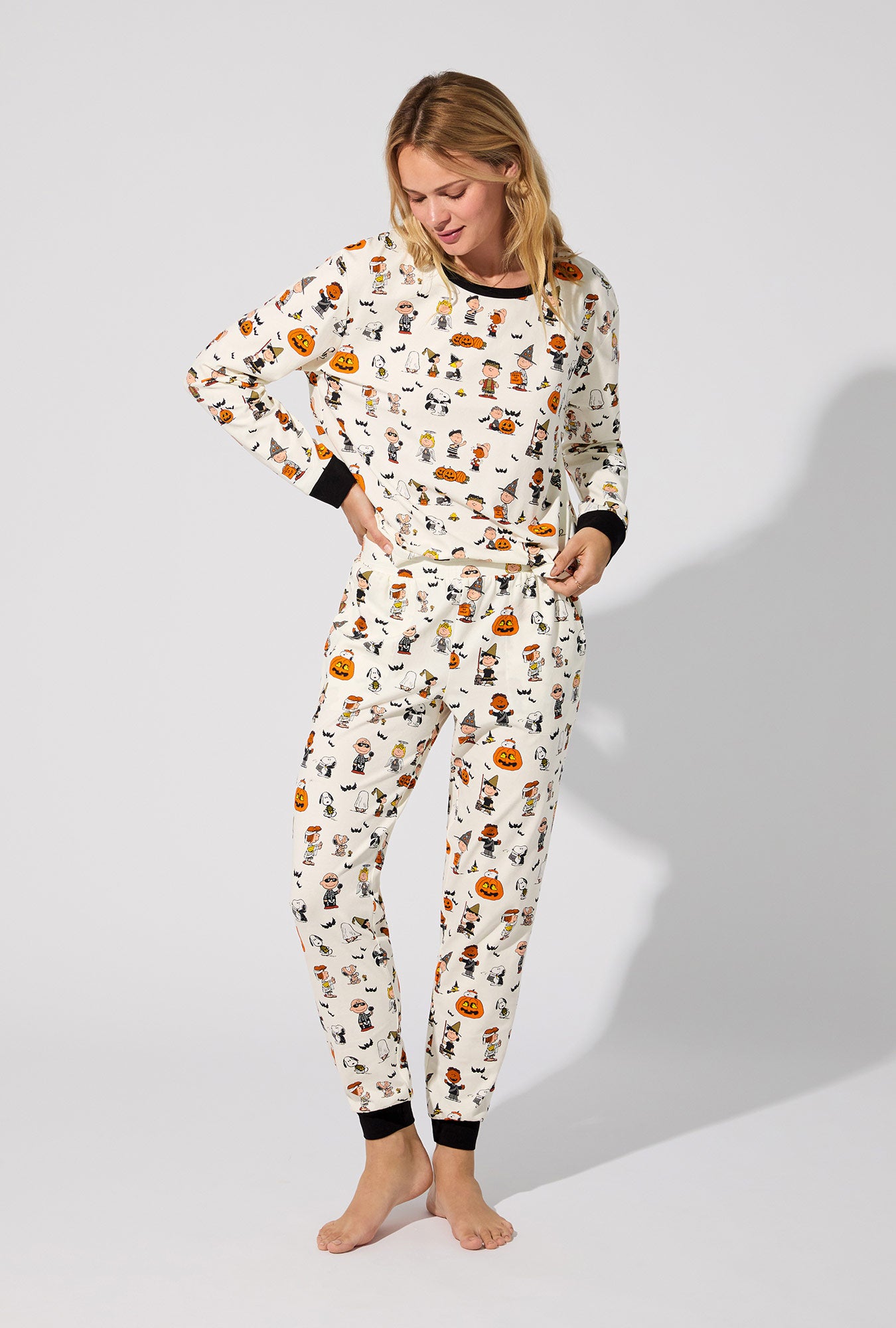 A lady wearing Peanuts® Snoopy's Halloween Long Sleeve Pullover Crew and Jogger Stretch Jersey PJ Set