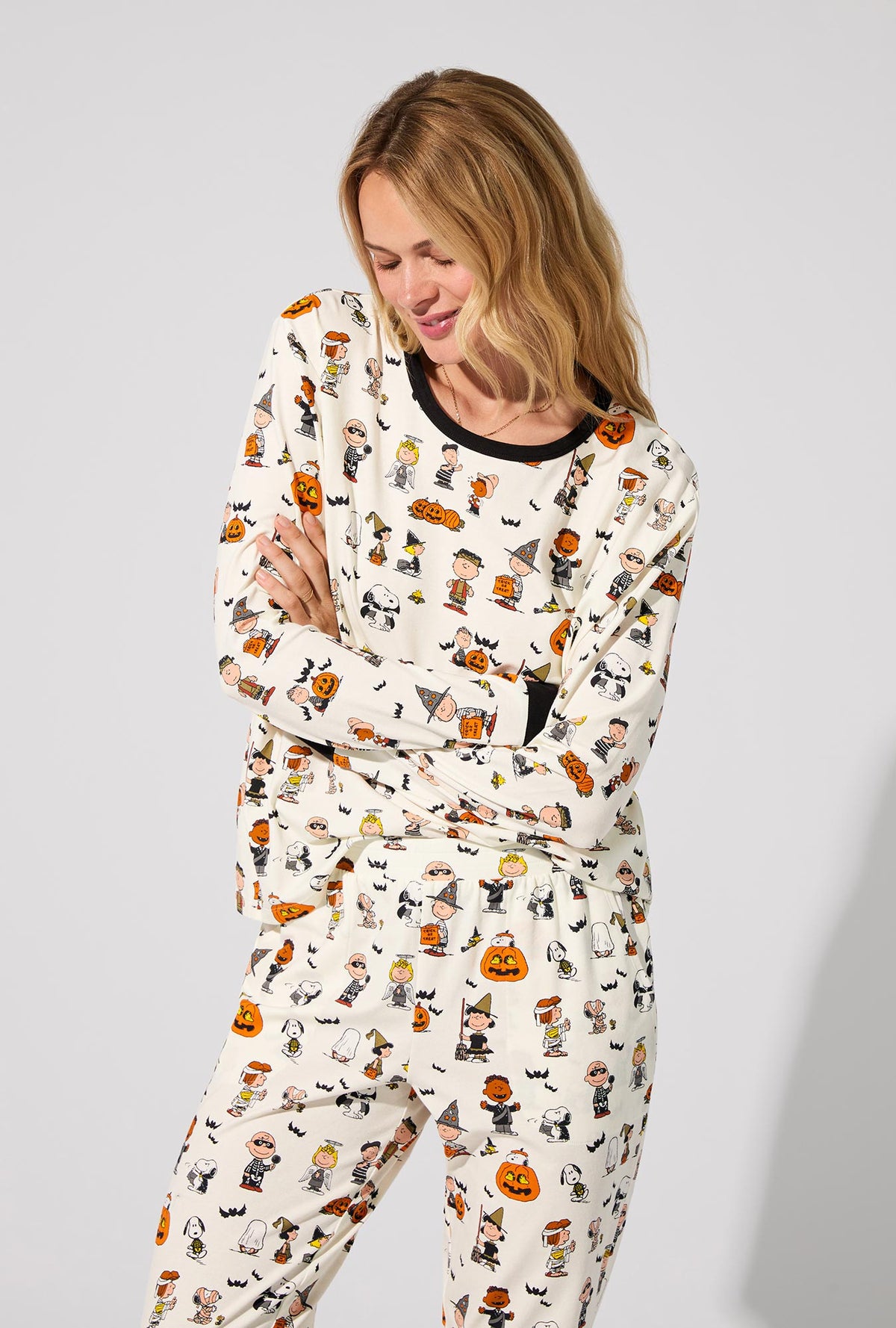 A lady wearing Peanuts® Snoopy&#39;s Halloween Long Sleeve Pullover Crew and Jogger Stretch Jersey PJ Set
