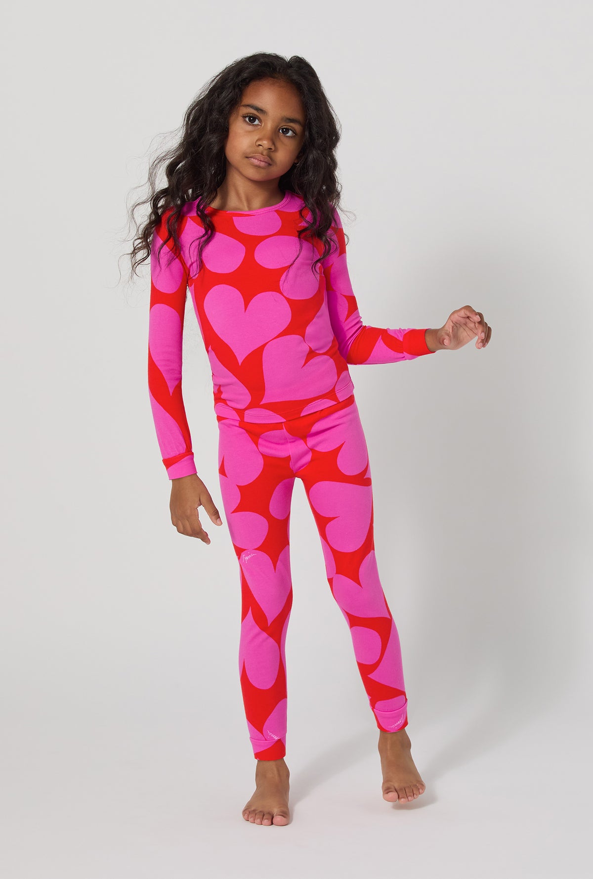A girl wearing BedHead x Trina Turk Hearts Long Sleeve Stretch Jersey Kids Pj Set