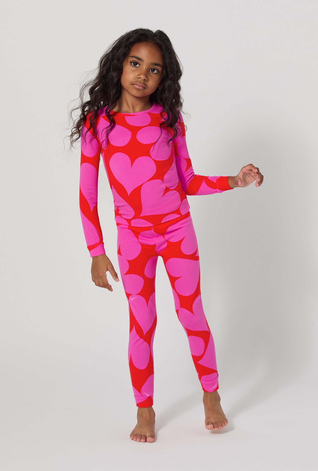 A girl wearing BedHead x Trina Turk Hearts Long Sleeve Stretch Jersey Kids Pj Set