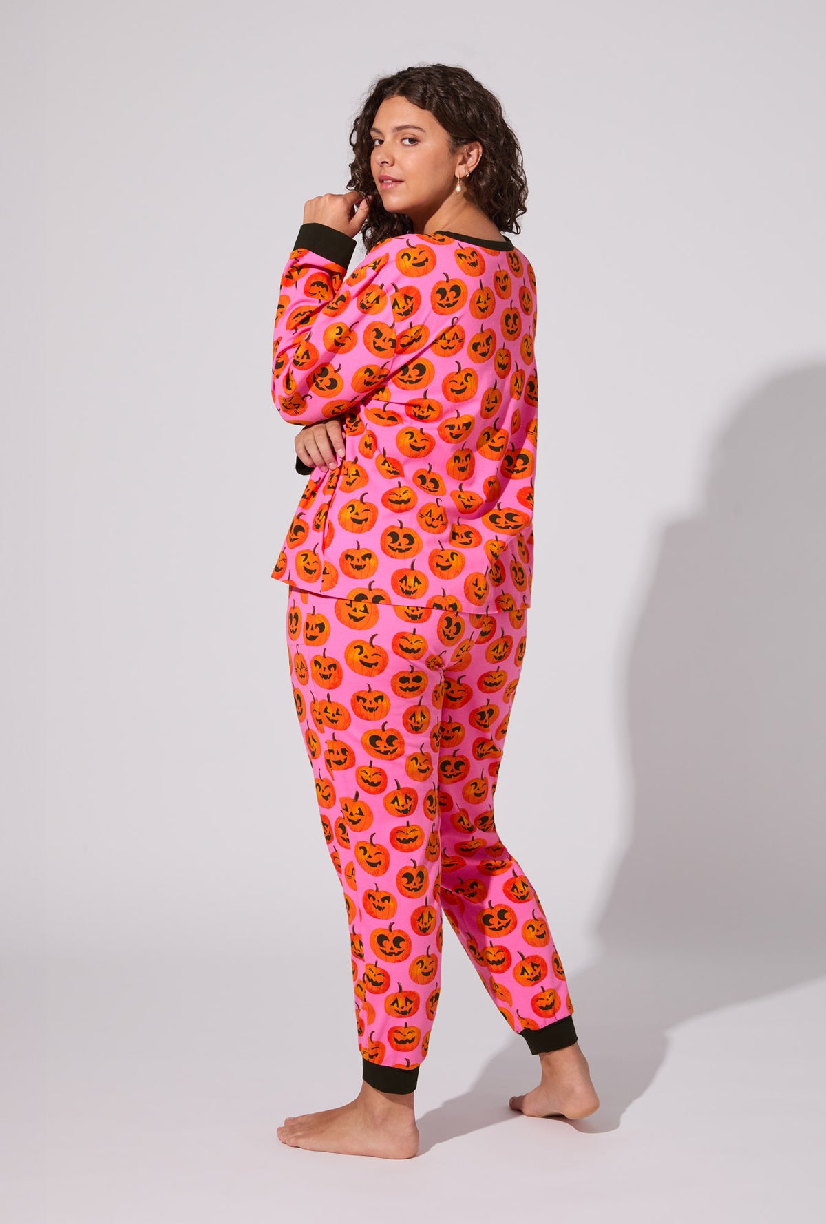 A lady wearing Jolly Jack-O-Lanterns Long Sleeve Pullover Crew and Jogger Stretch Jersey PJ Set