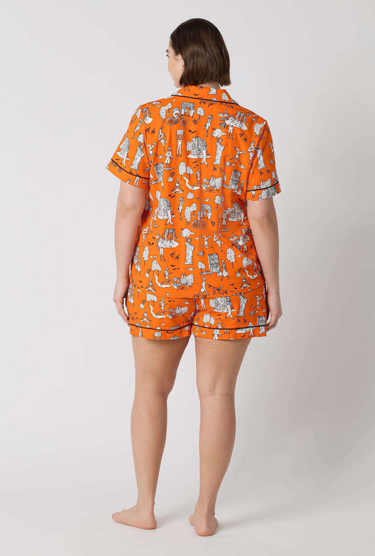A Lady Wearing Plus Size Orange Spooky In The City Short Sleeve Classic Shorty Stretch Jersey Pj Set in a back view pose