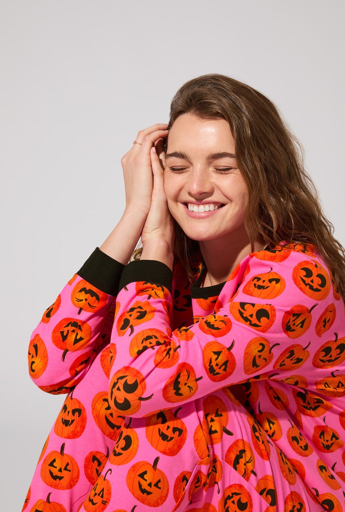 A lady wearing Jolly Jack-O-Lanterns Long Sleeve Pullover Crew and Jogger Stretch Jersey PJ Set