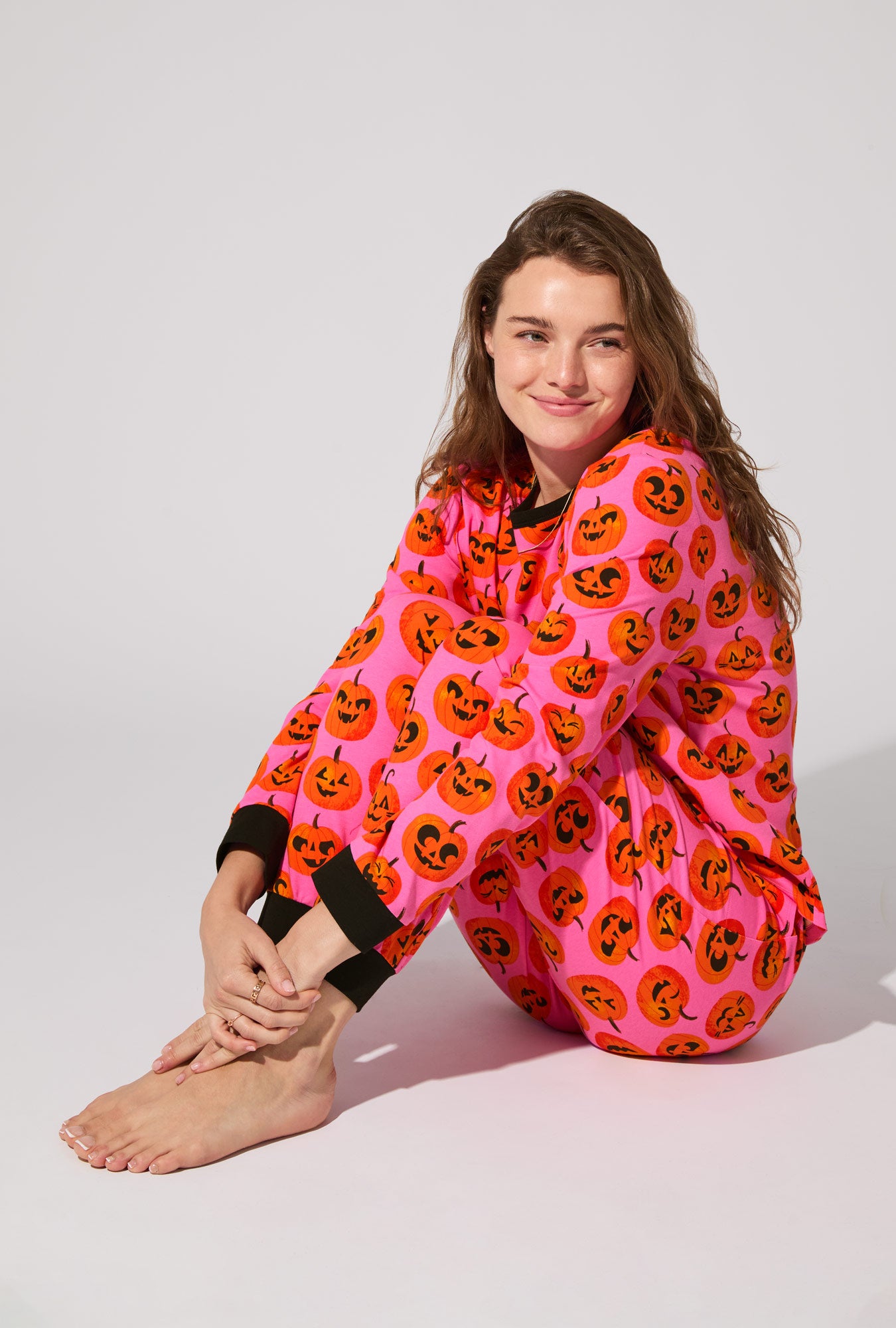 A lady wearing Jolly Jack-O-Lanterns Long Sleeve Pullover Crew and Jogger Stretch Jersey PJ Set