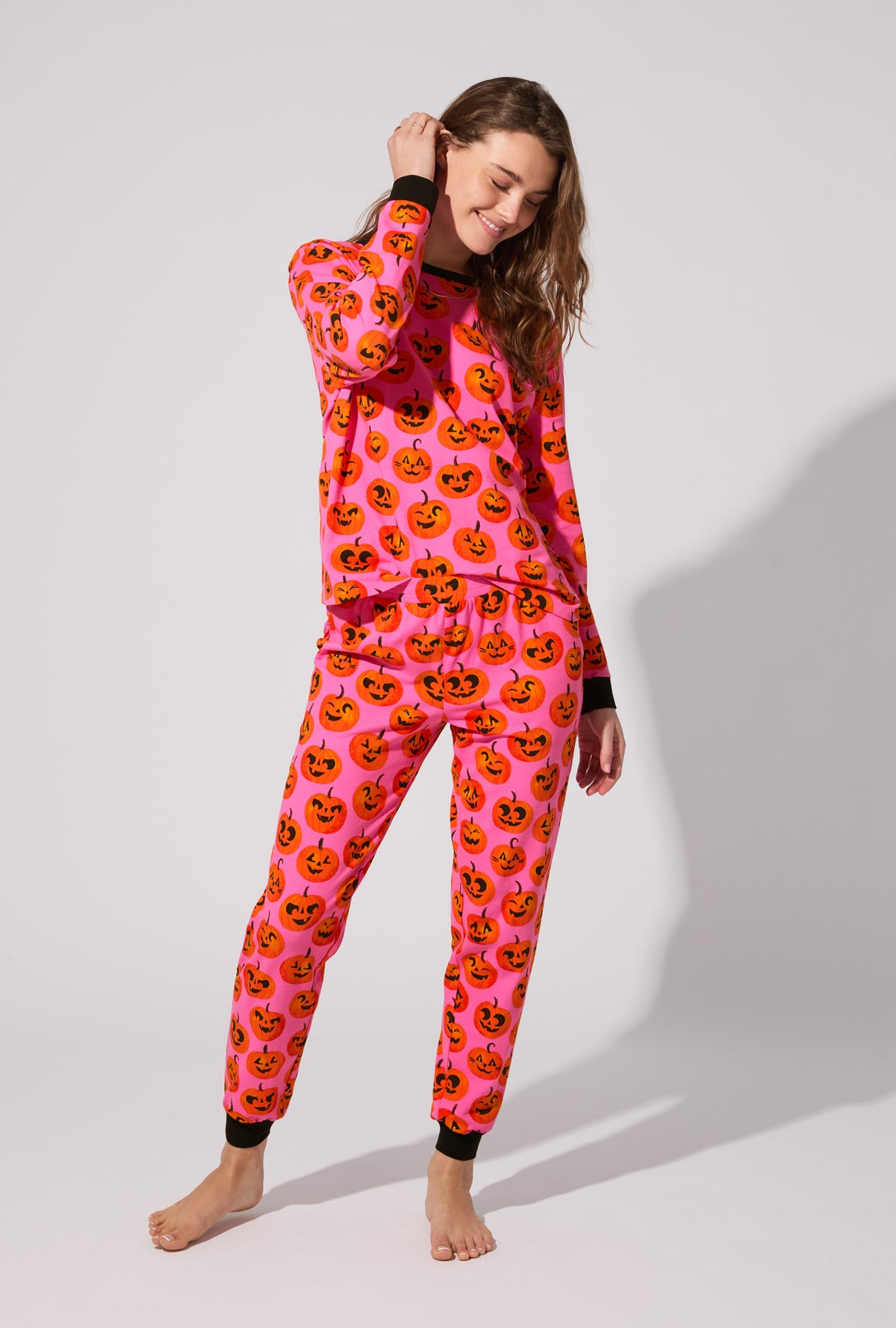 A lady wearing Jolly Jack-O-Lanterns Long Sleeve Pullover Crew and Jogger Stretch Jersey PJ Set