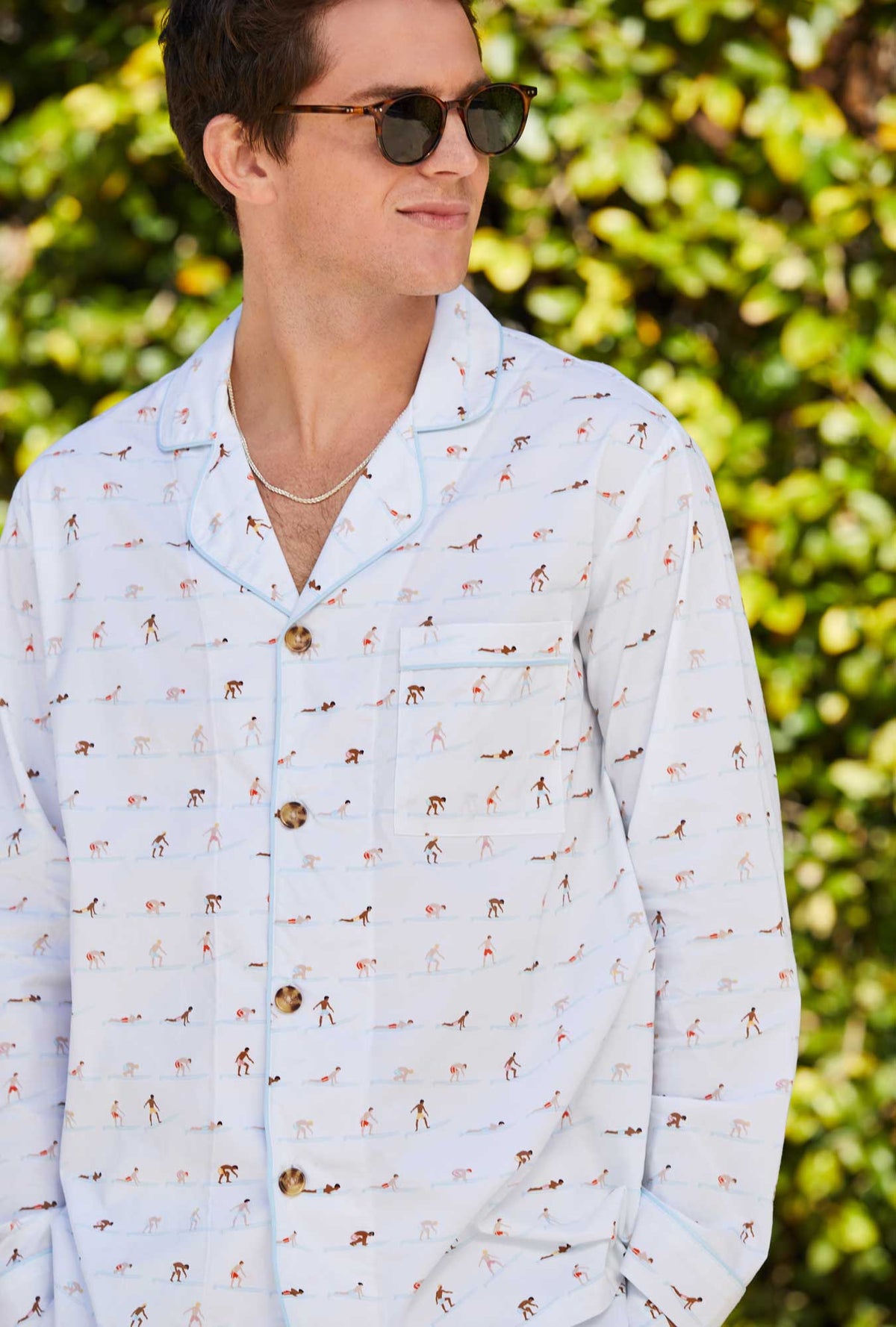 A man wearing white long sleeve classic woven cotton poplin pj set with surf&#39;s up print.