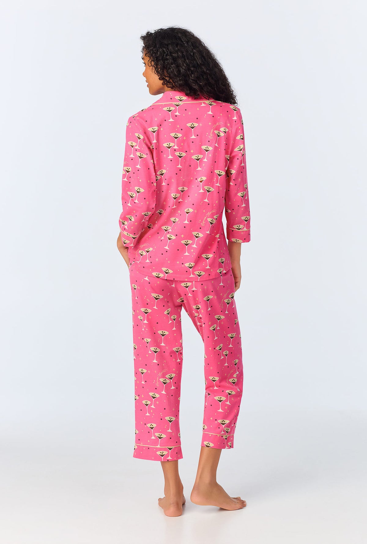 A lady wearing pink long sleeve pajama set with espresso martini print.