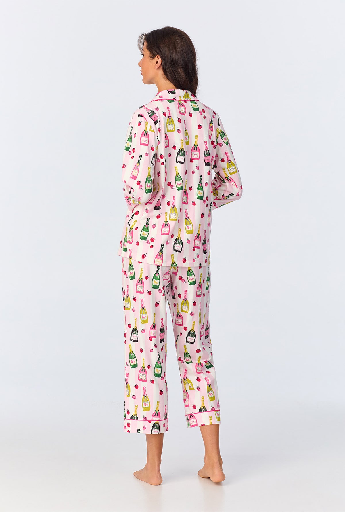 A lady wearing pink quarter sleeve pajama set with champagne toast print.