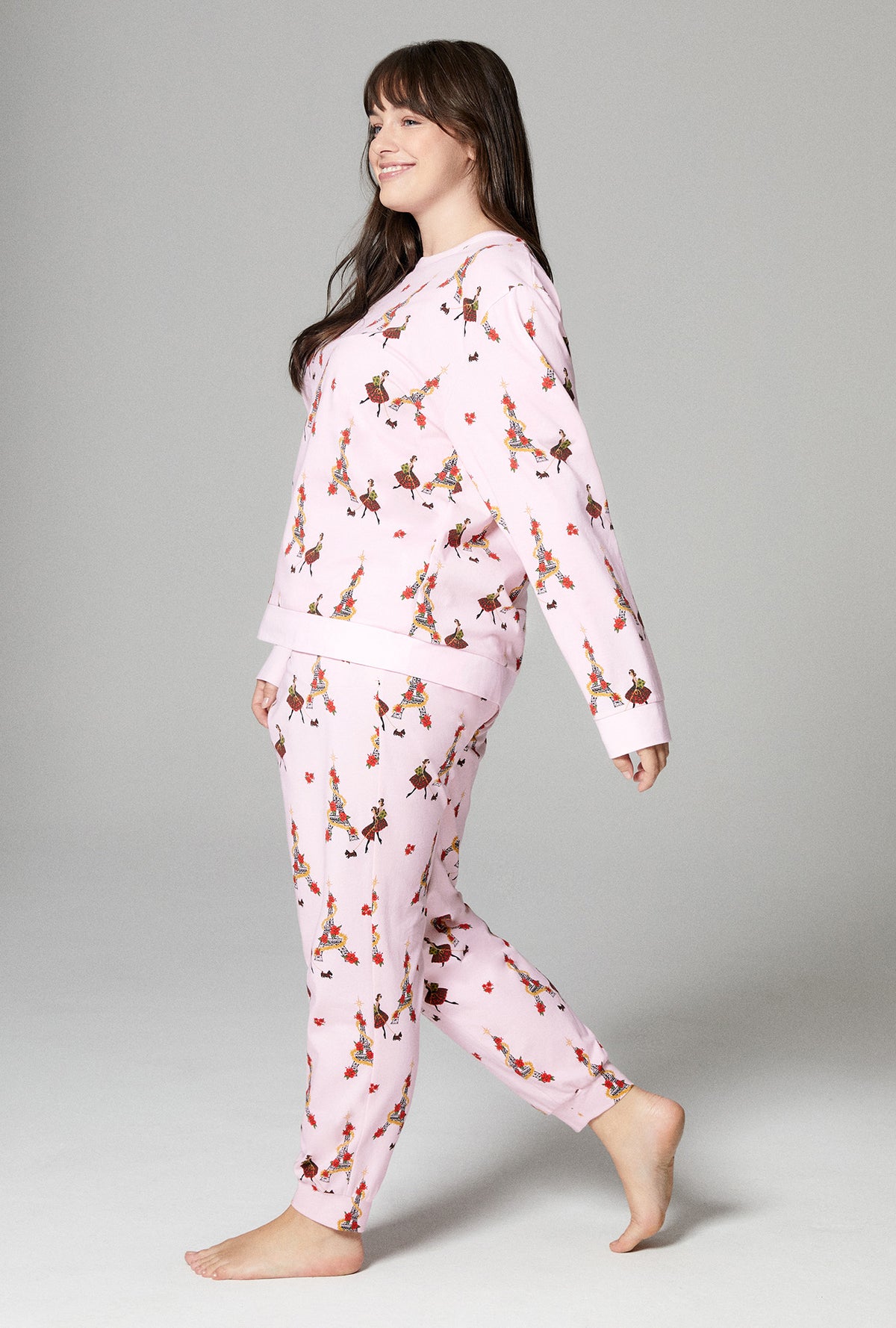 A lady wearing pink long sleeve pullover crew and jogger stretch jersey plus pj set with christmas chic print.
