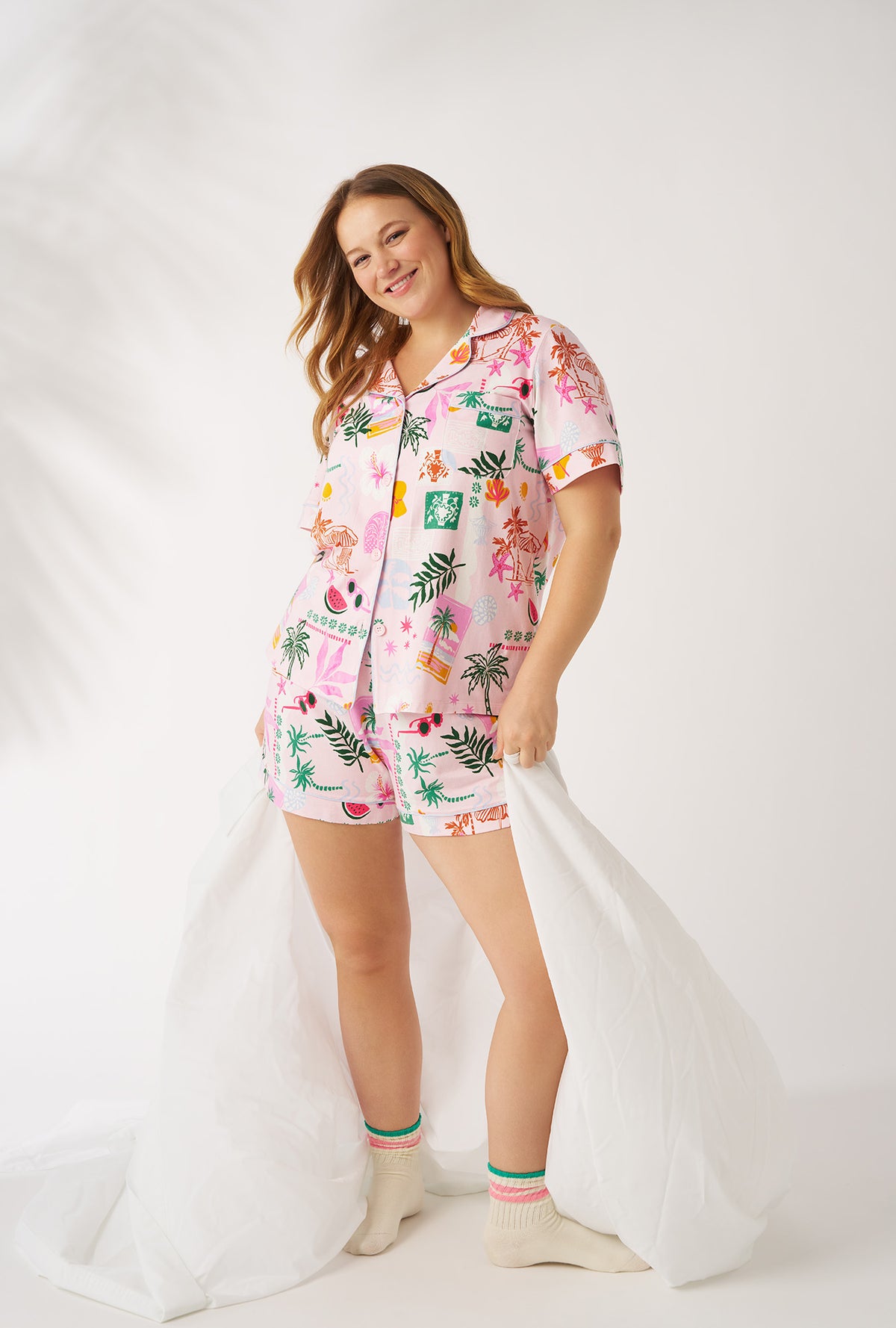 A Lady Wearing Plus Size Tropical Daydream Short Sleeve Classic Shorty Stretch Jersey Pj Set posing with a white fabric around the low hip