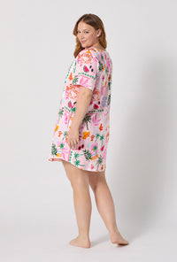 A Lady Wearing Plus Size Tropical Daydream Stretch Jersey T-shirt Sleep Dress posing back view while looking back over the shoulder