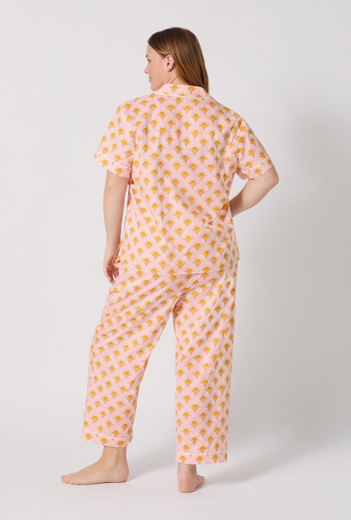 A Lady Wearing Plus Size Deco Sunset Short Sleeve Classic Woven Cotton Poplin Cropped Pj Set posing with a back view