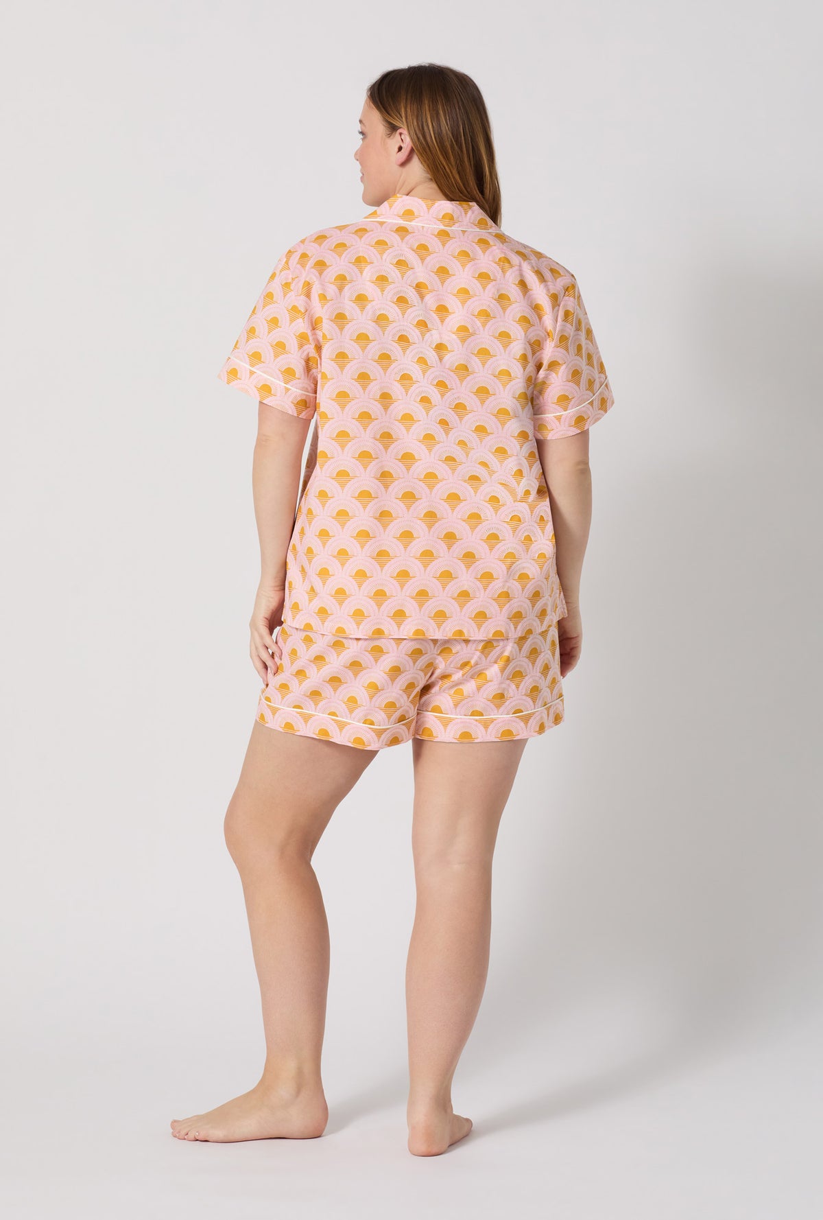 A Lady Wearing Plus Size Deco Sunset Short Sleeve Classic Woven Cotton Poplin Shorty Pj Set posing with a back view look