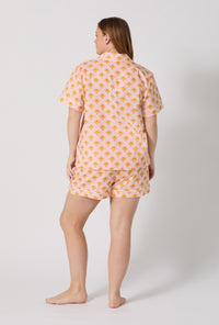 A Lady Wearing Plus Size Deco Sunset Short Sleeve Classic Woven Cotton Poplin Shorty Pj Set posing with a back view look