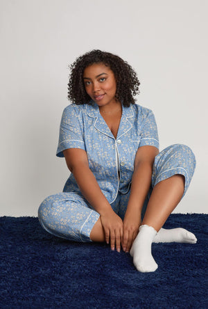 A lady sitting wearing Blue Short Sleeve Classic Woven Tana Lawn® Cropped plus size Pj Set Made With Liberty Fabric front view