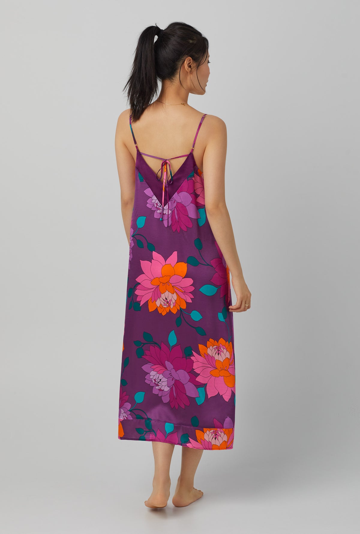 A lady wearing purple long sleeve maxi washable silk chemise with trina turk evening blooms print.