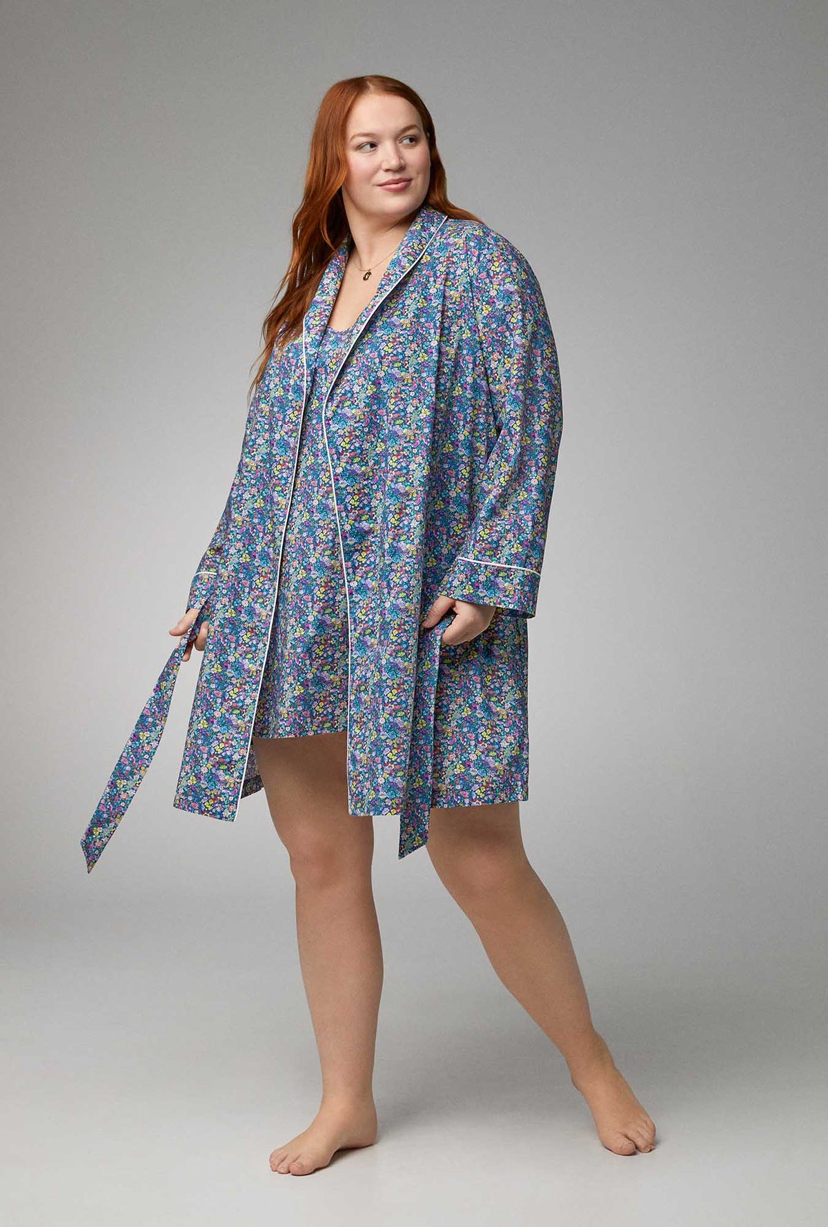 A lady wearing blue long sleeve shawl collar classic woven tana lawn plus size robe made with liberty fabrics with classic garden print.