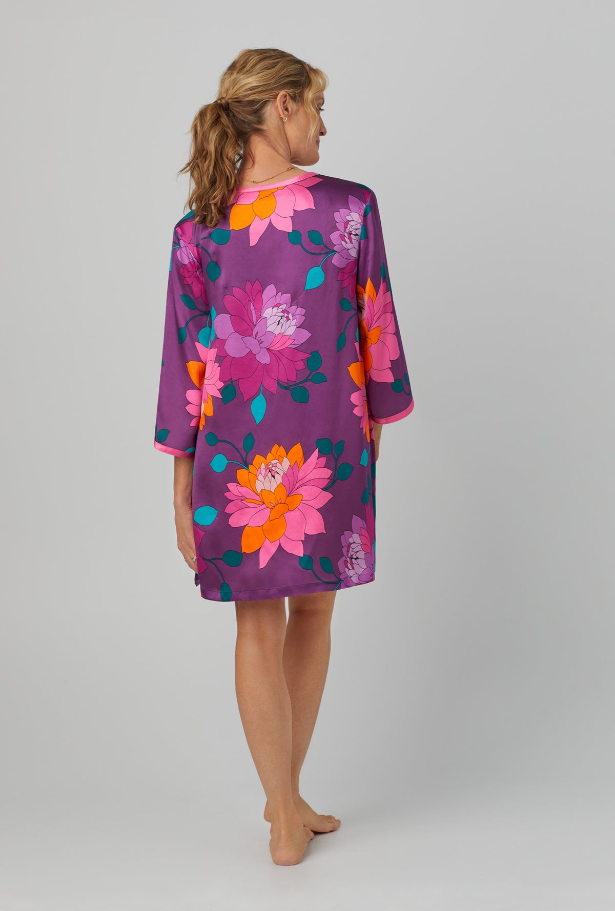 A lady wearing purple qurter sleeve classic washable silk caftan with trina turk evening blooms print.