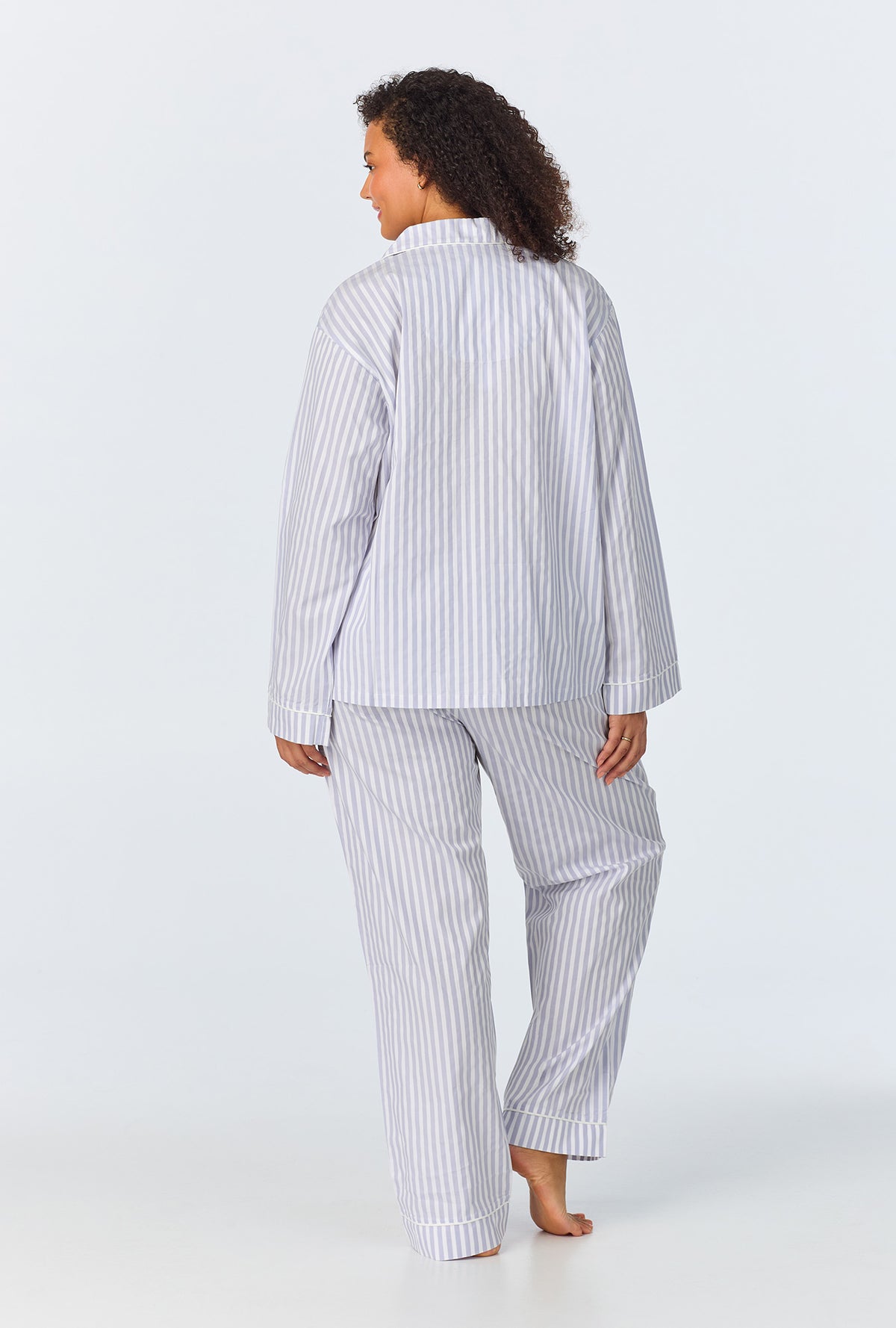A lady wearing a long sleeve plus cotton sateen pj set with blue and white stripe pattern.