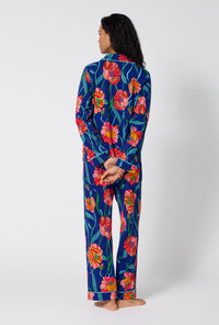 A Lady Wearing BedHead x Trina Turk Linear Poppy Long Sleeve Classic Stretch Jersey Pj Set in a back view pose