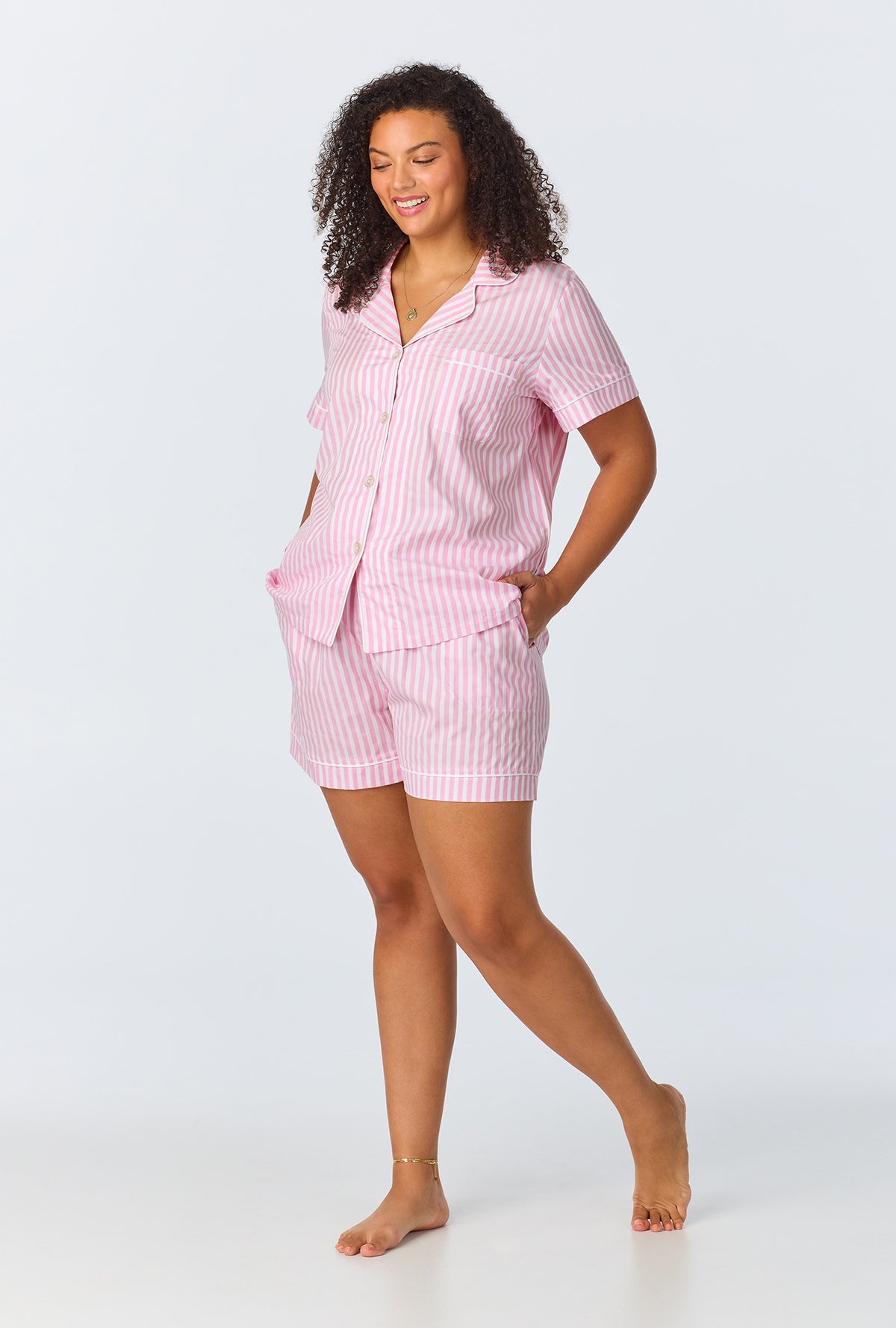 A lady wearing a plus size pink and white stripes short sleeve shorty pj set.