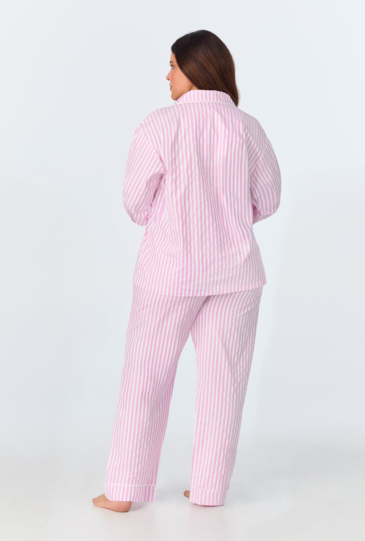 A lady wearing a pink and white stripes Plus long sleeve pj set.