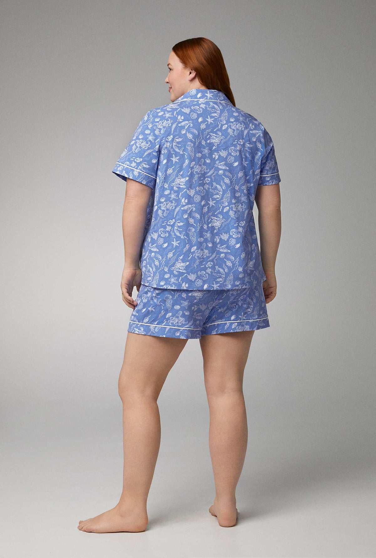 A lady wearing blue short sleeve classic shorty stretch jersey plus size pj set with high tide print.