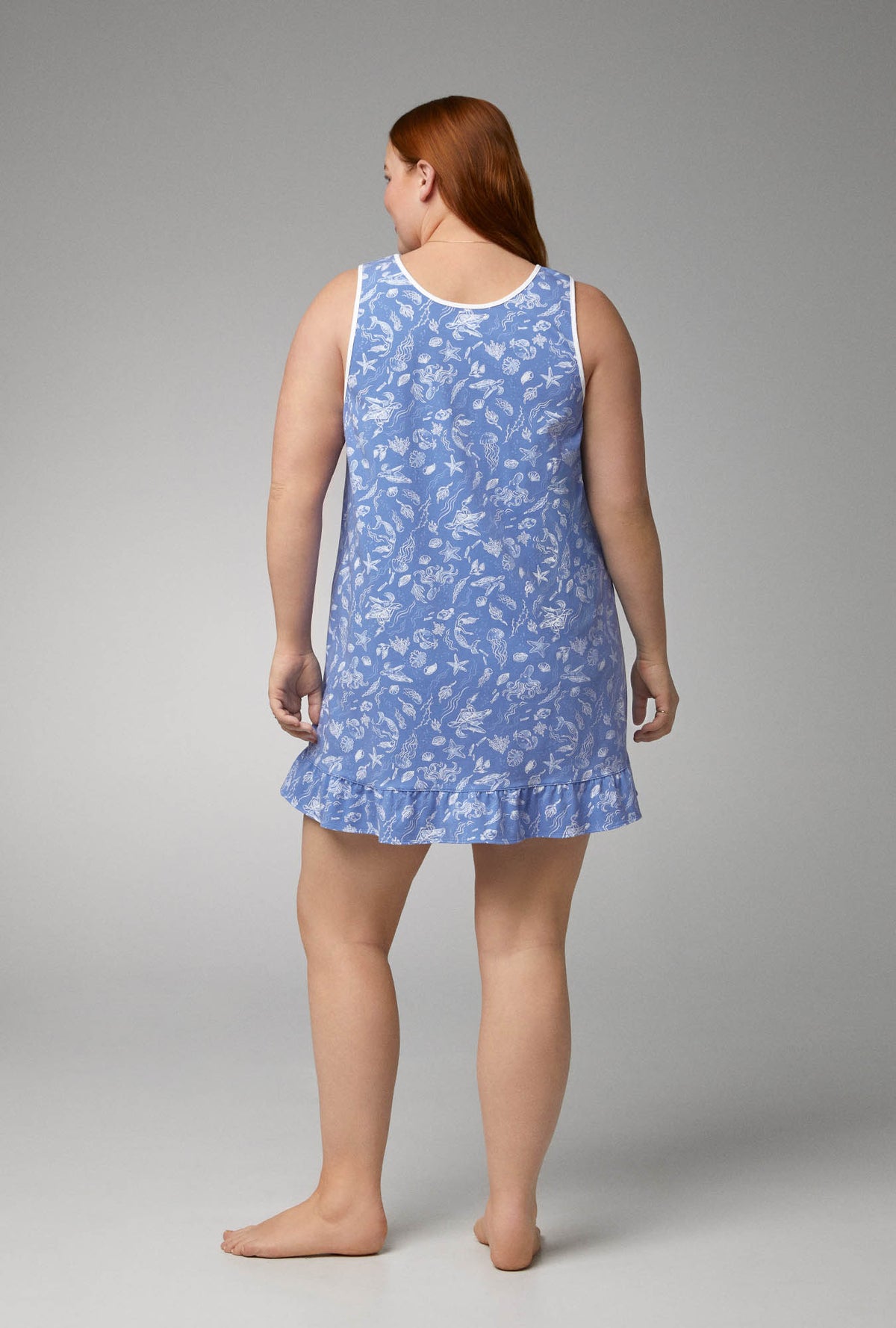 A lady wearing blue sleeveless ruffle stretch jersey plus size chemise with high tide print.