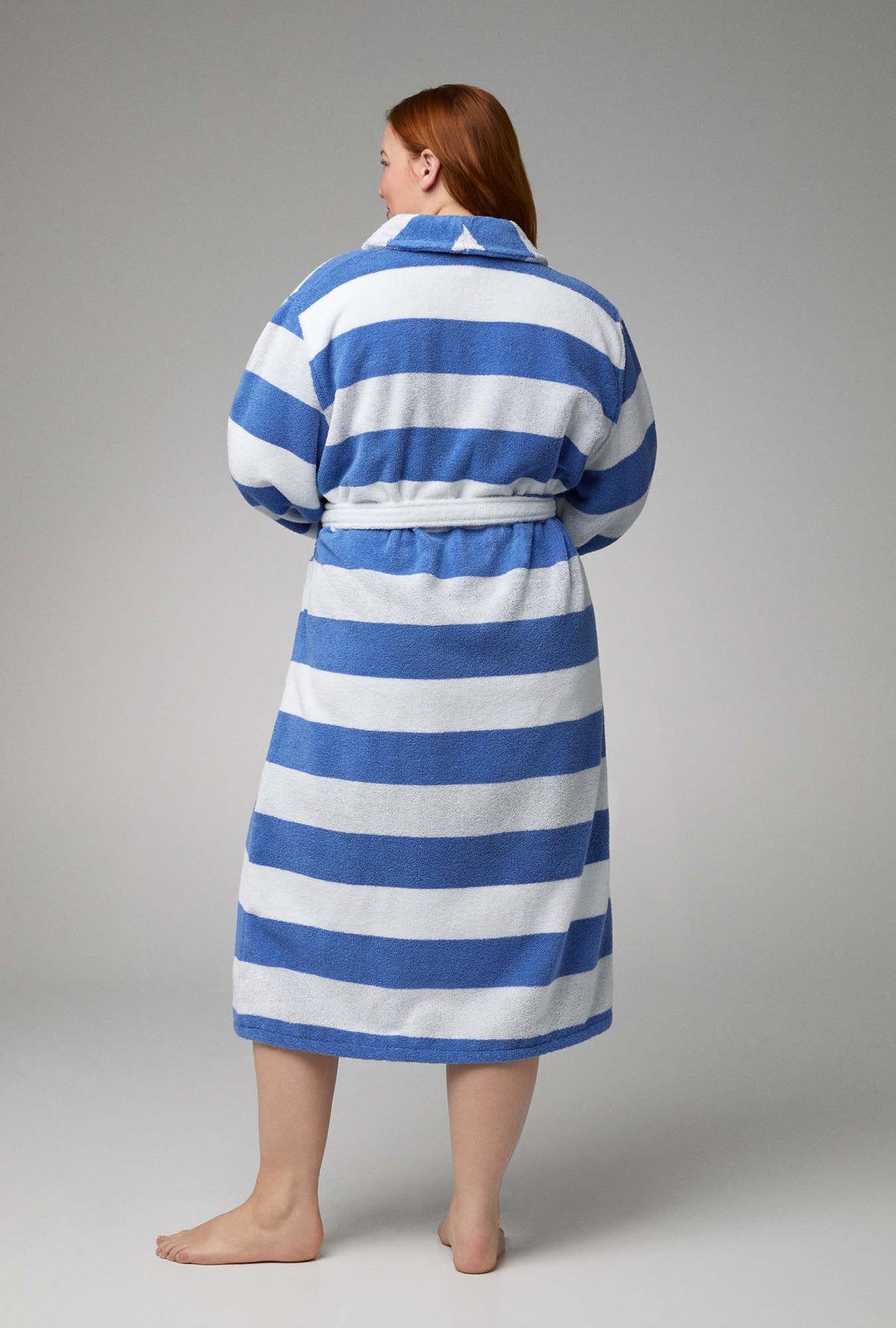 A lady wearing white and blue unisex woven cotton loop turkish terry jacquard long robe with seaside stripe print.