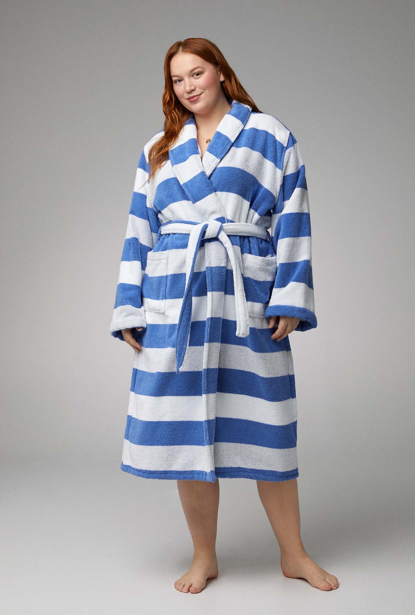 A lady wearing white and blue unisex woven cotton loop turkish terry jacquard long robe with seaside stripe print.