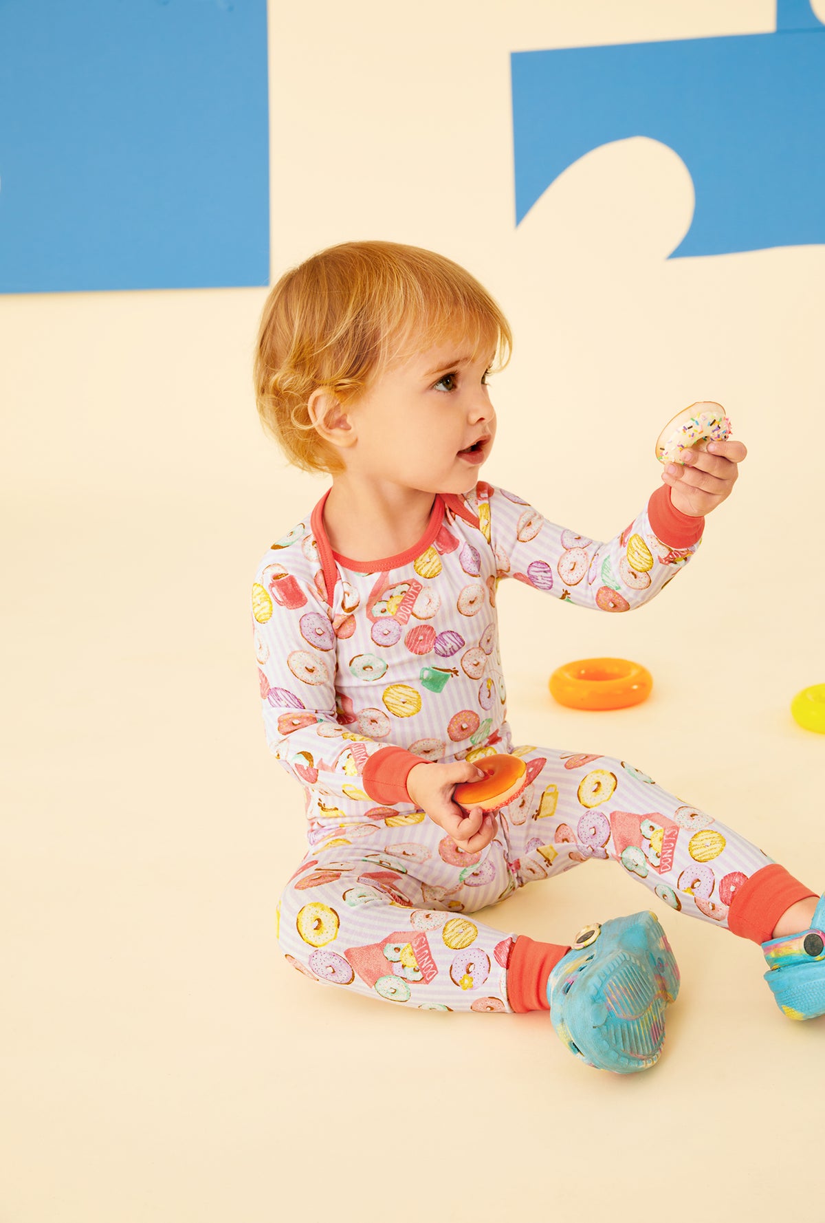 A baby wearing a purple long sleeve pajama set with donuts pattern.
