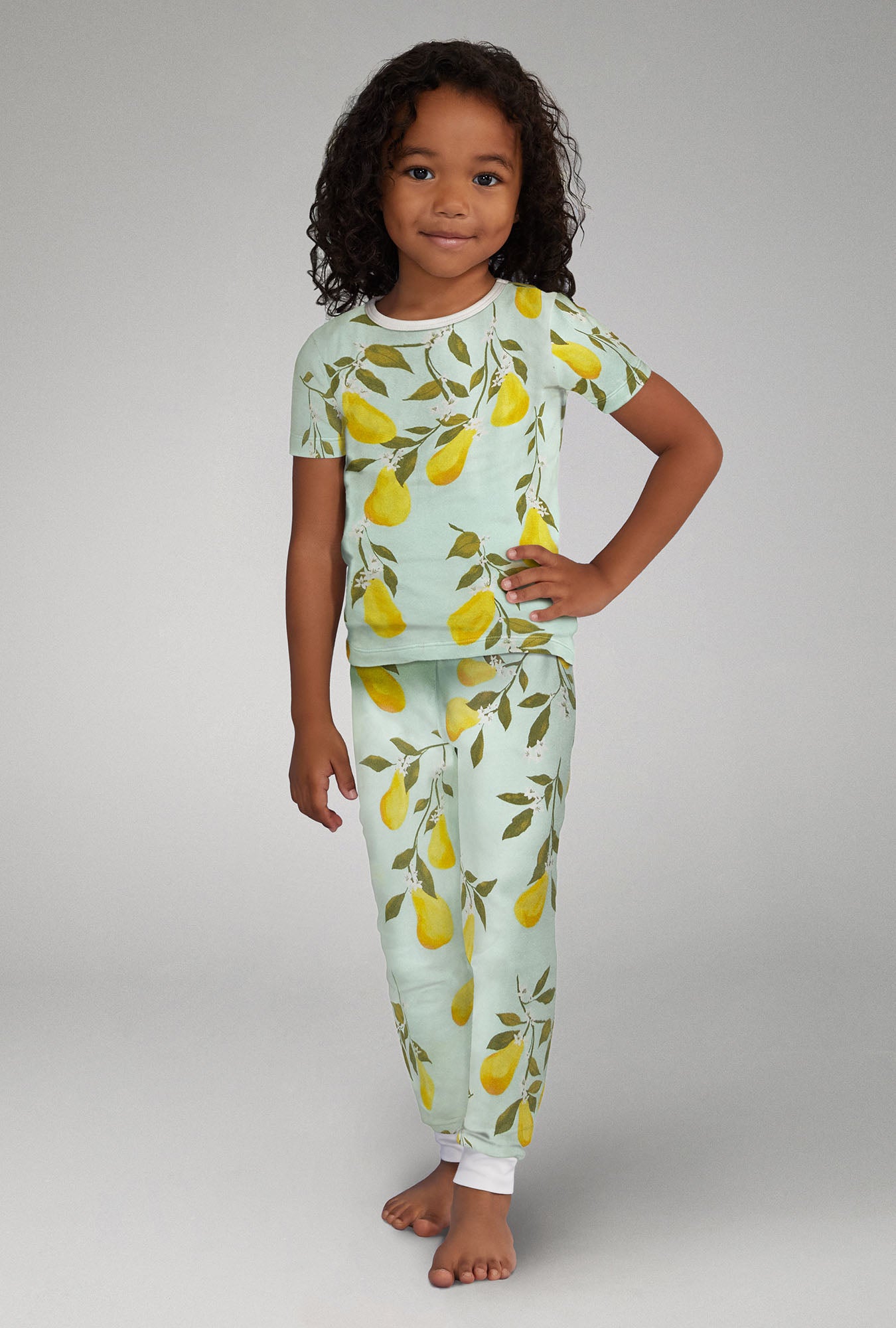A girl wearing green Short Sleeve Stretch Jersey Kids PJ Set with Pear Tree print