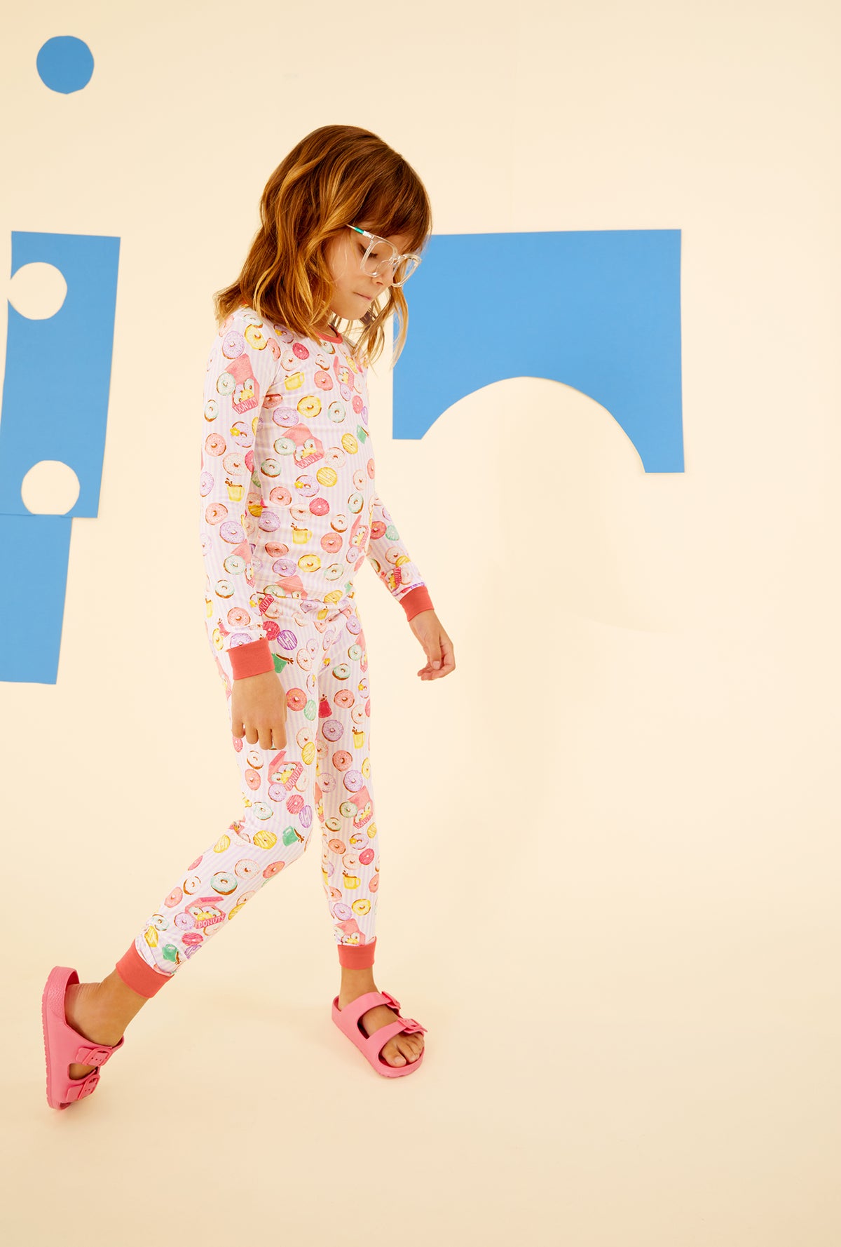  A kid wearing a purple long sleeve pajama set with donuts pattern.