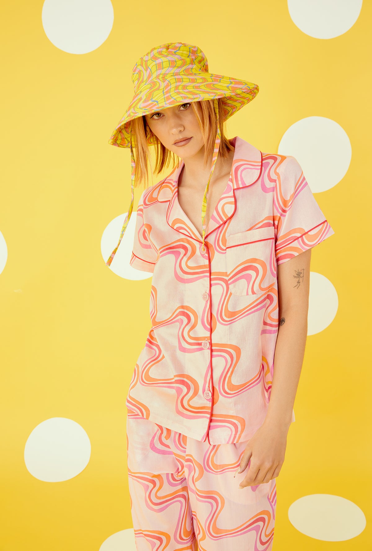 A lady wearing a orange pink short sleeve cropped pajama set with swirl pattern.