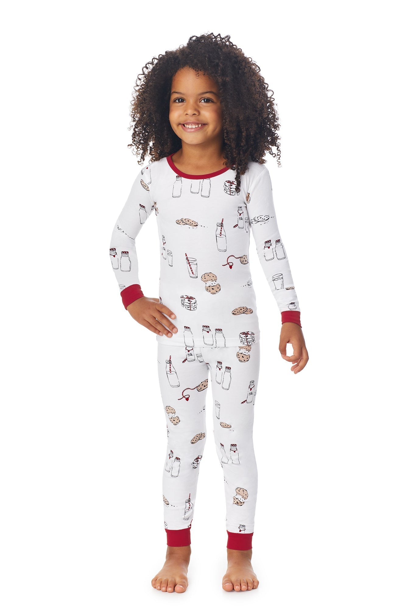 A girl wearing a white long sleeve pj set with milk and cookies pattern. 