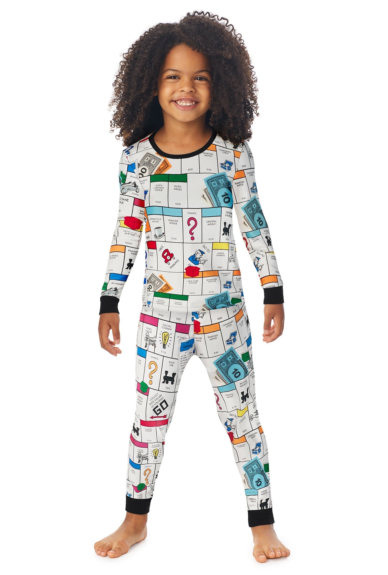 A girl wearing a white long sleeve pj set with monopoly gameboard pattern.