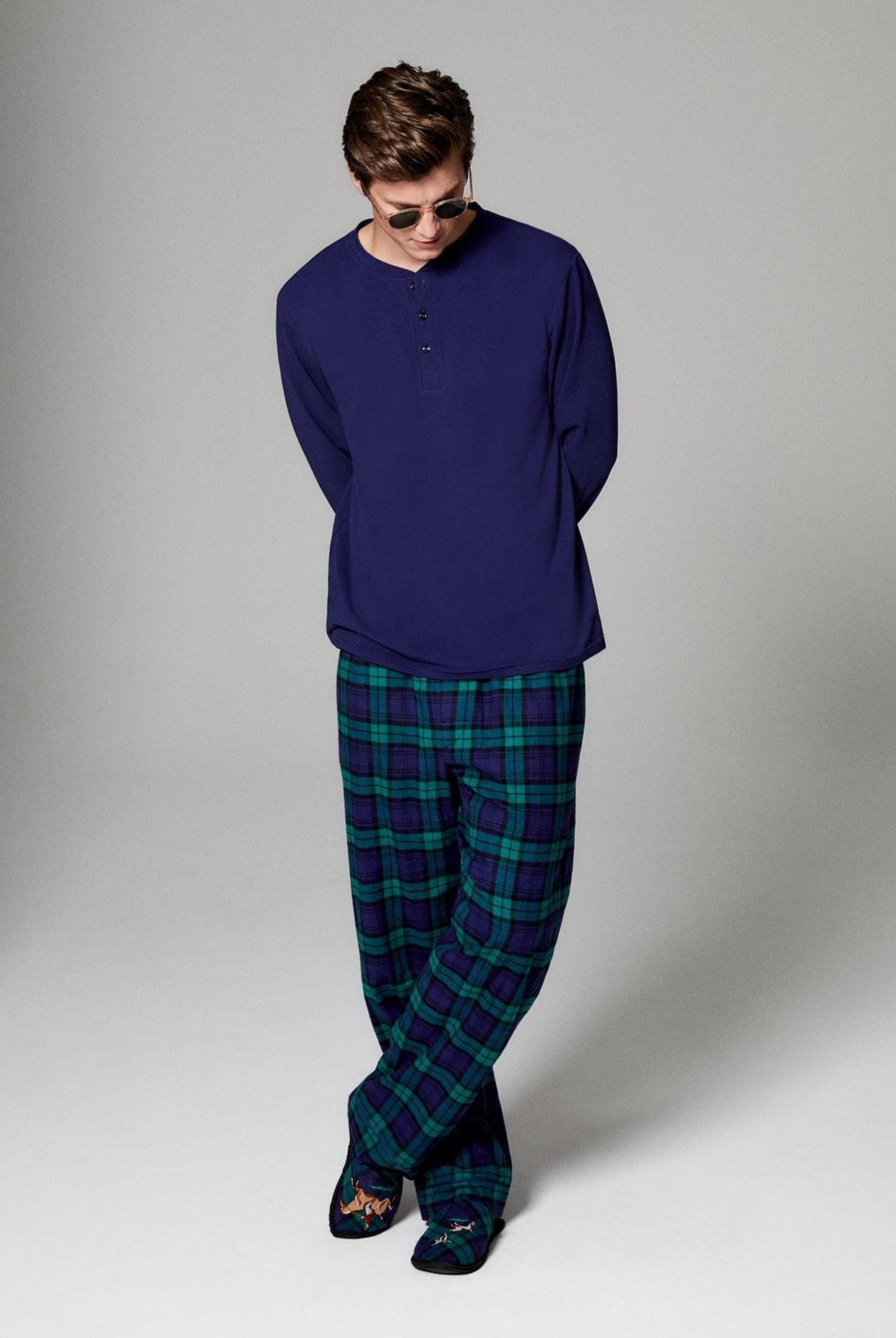 A man wearing navy long sleeve henley woven cotton portuguess flannel pj set with highlander print.