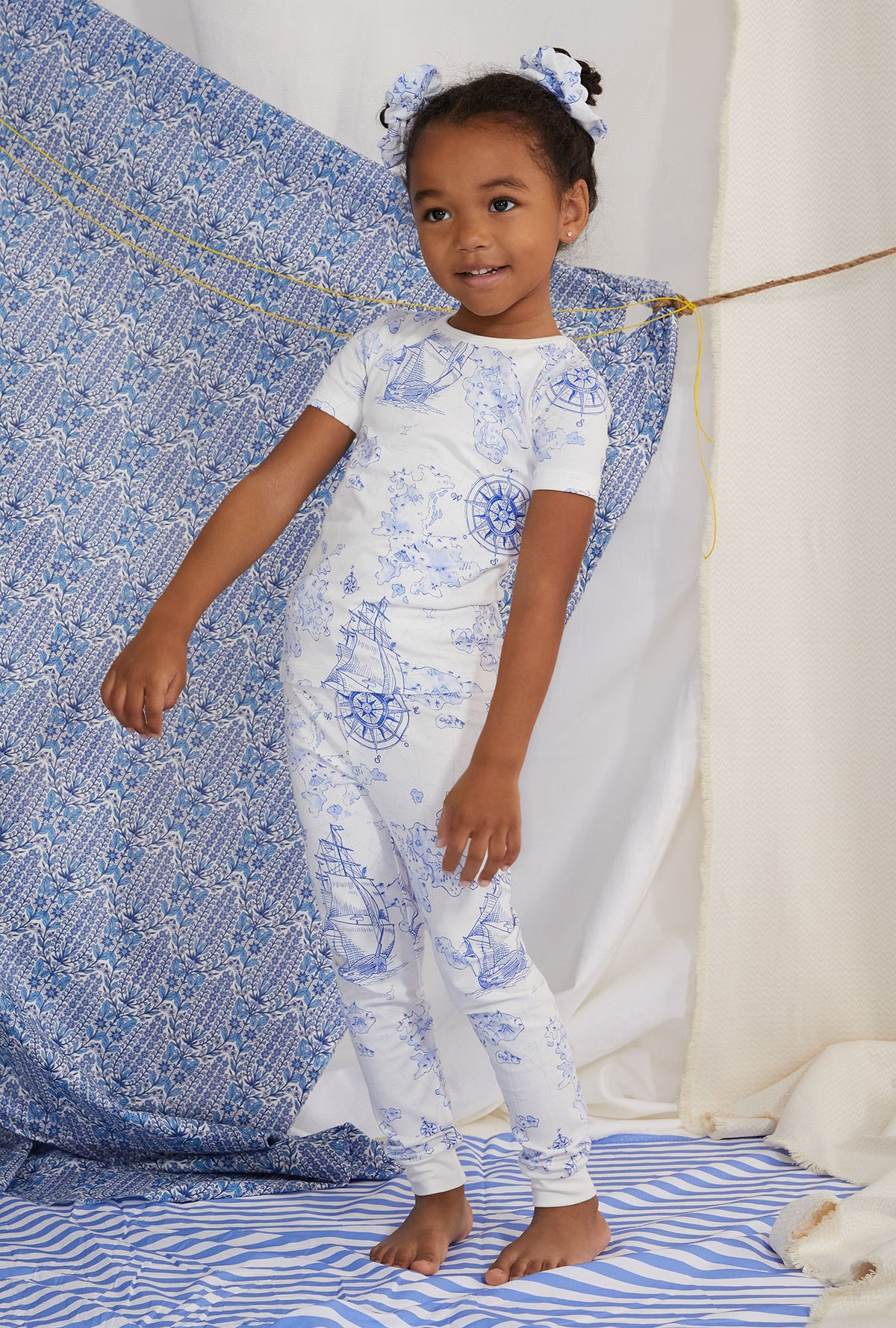 A kid wearing white short sleeve pj set with voyager print.